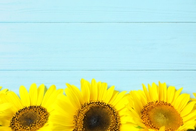 Photo of Yellow sunflowers on wooden background, top view