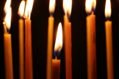 Photo of Many burning church candles on dark background, closeup