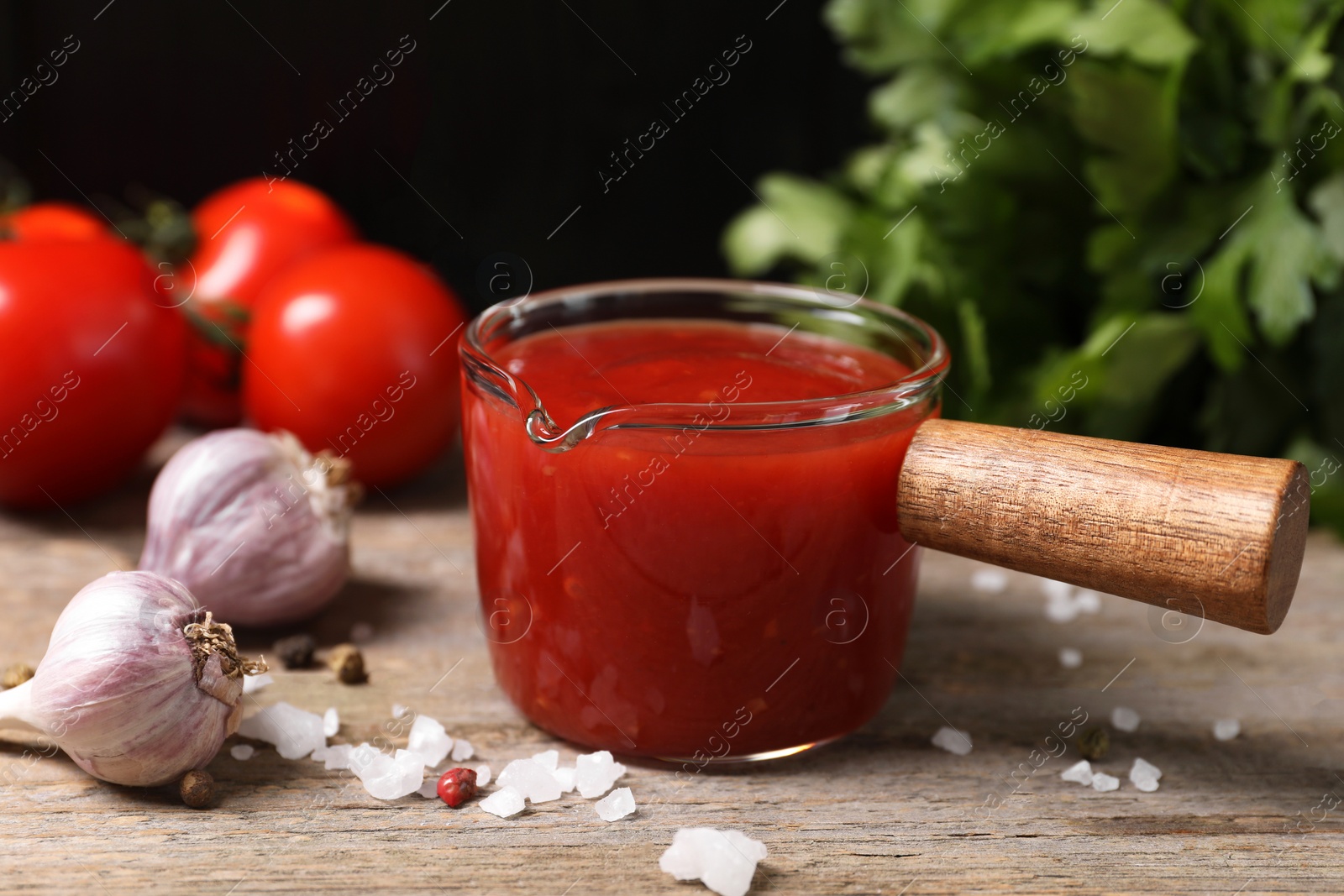 Delicious ketchup, salt and garlic on wooden table, closeup. Tomato sauce Photo of Delicious ketchup, salt and garlic on wooden table, closeup. Tomato sauce
