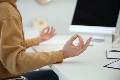 Photo of Man meditating at desk in light office, closeup