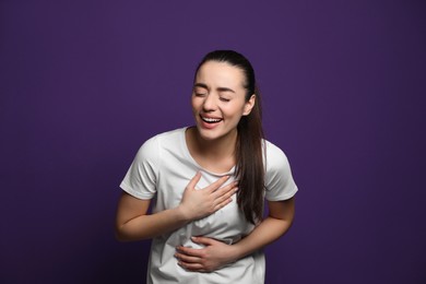 Photo of Beautiful young woman laughing on purple background. Funny joke