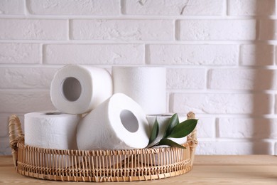 Photo of Toilet paper rolls and green leaves on wooden table near white brick wall