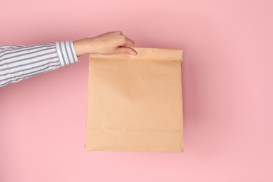 Photo of Woman holding paper bag on color background. Mockup for design