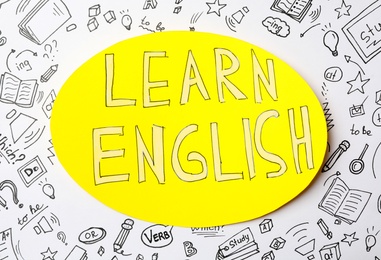 Note with phrase Learn English and drawings on white background, top view