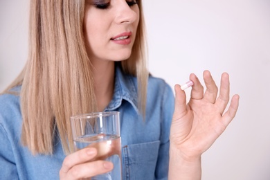 Young woman with pill indoors