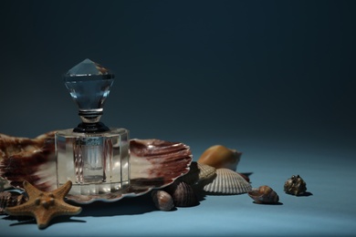 Photo of Perfume bottle, sea shells and starfish on blue background. Space for text