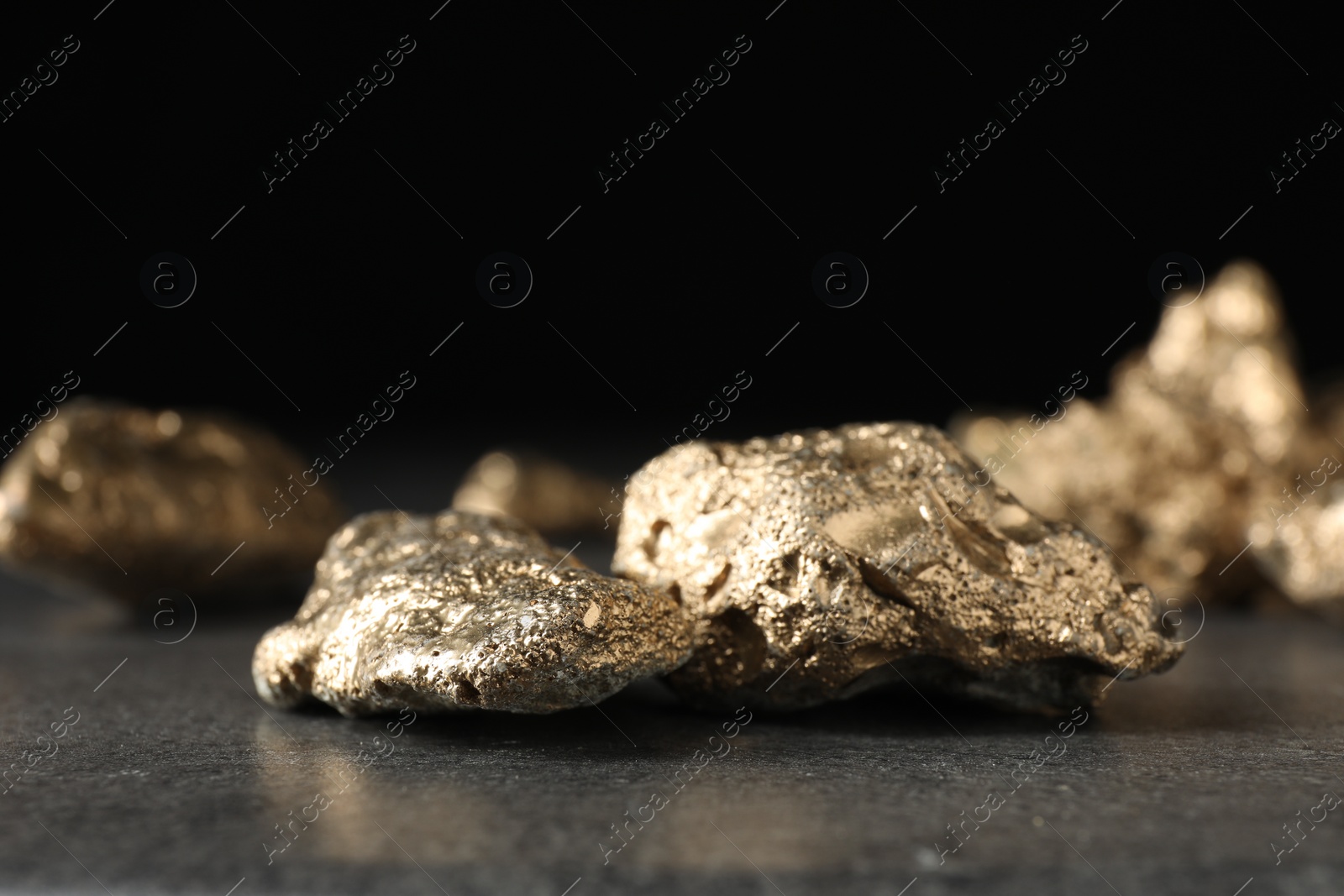 Photo of Shiny gold nuggets on grey textured surface, closeup
