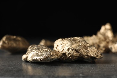 Shiny gold nuggets on grey textured surface, closeup