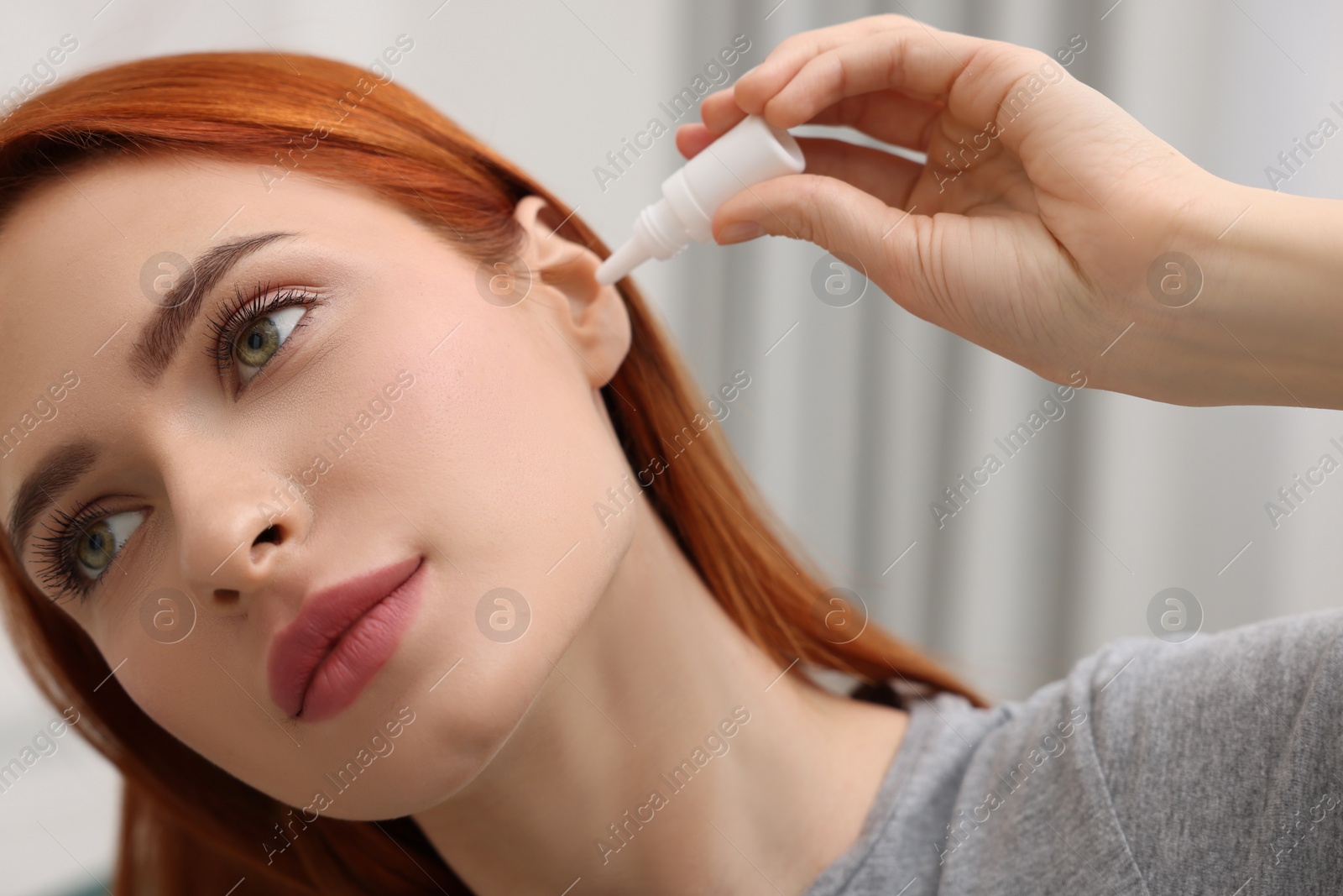 Photo of Woman applying medical ear drops at home