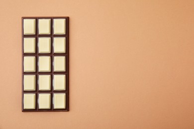 Photo of Tasty chocolate bar on brown background, top view. Space for text