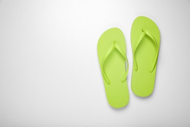 Photo of Light green flip flops on white background, top view. Space for text