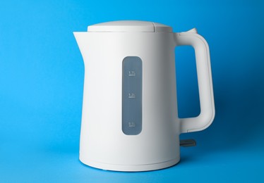 Modern electric kettle on light blue background
