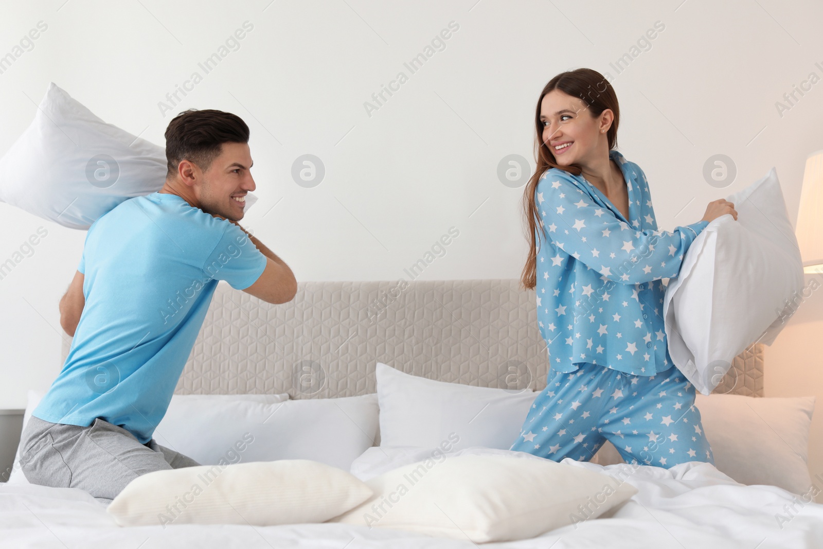 Photo of Happy couple having pillow fight in bedroom