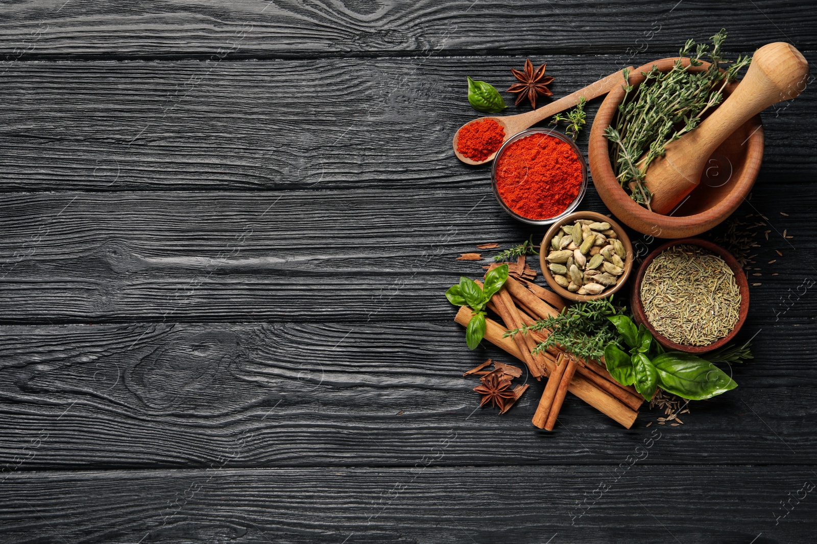 Photo of Different natural spices and herbs on black wooden table, flat lay. Space for text