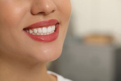 Photo of Happy young woman with white teeth on blurred background, closeup