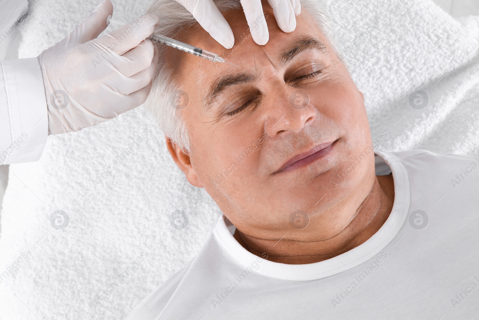 Photo of Senior man getting facial injection in clinic. Cosmetic surgery concept