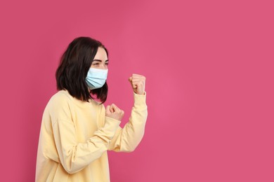 Photo of Woman with protective mask in fighting pose on pink background, space for text. Strong immunity concept