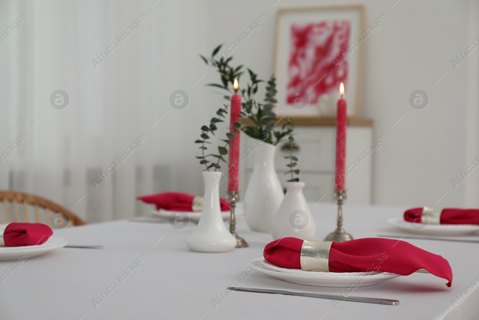 Photo of Beautiful table setting with green branches in vases and burning candles indoors. Stylish dining room