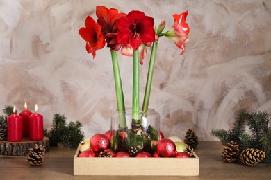 Photo of Beautiful red amaryllis flowers and Christmas decor on wooden table