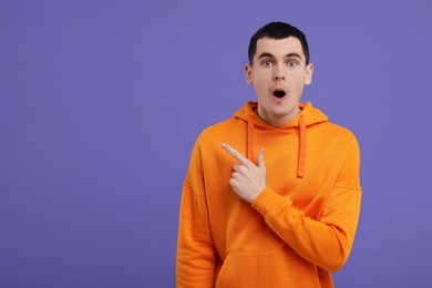 Portrait of surprised man on purple background, space for text