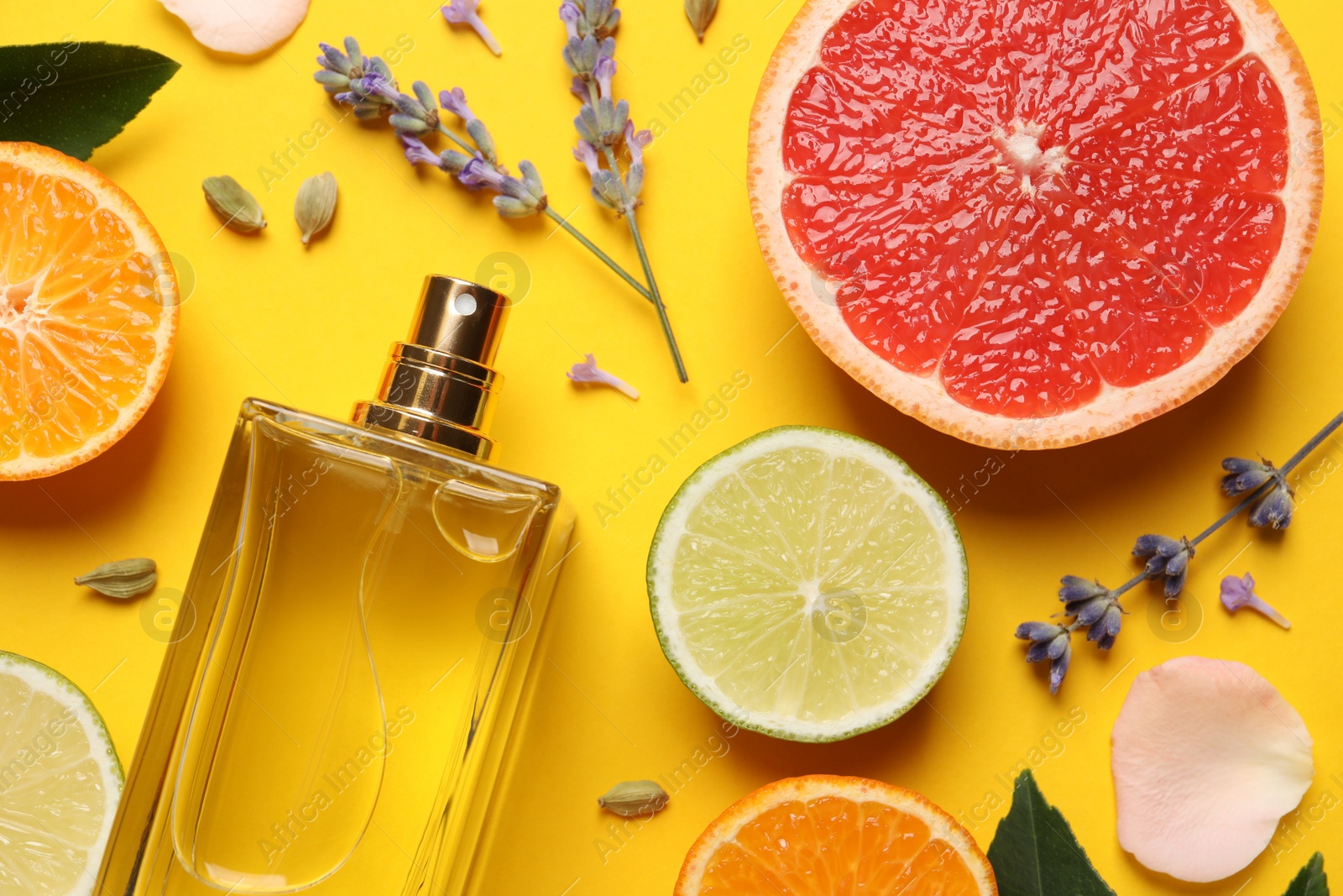 Photo of Flat lay composition with bottle of perfume and fresh citrus fruits on yellow background