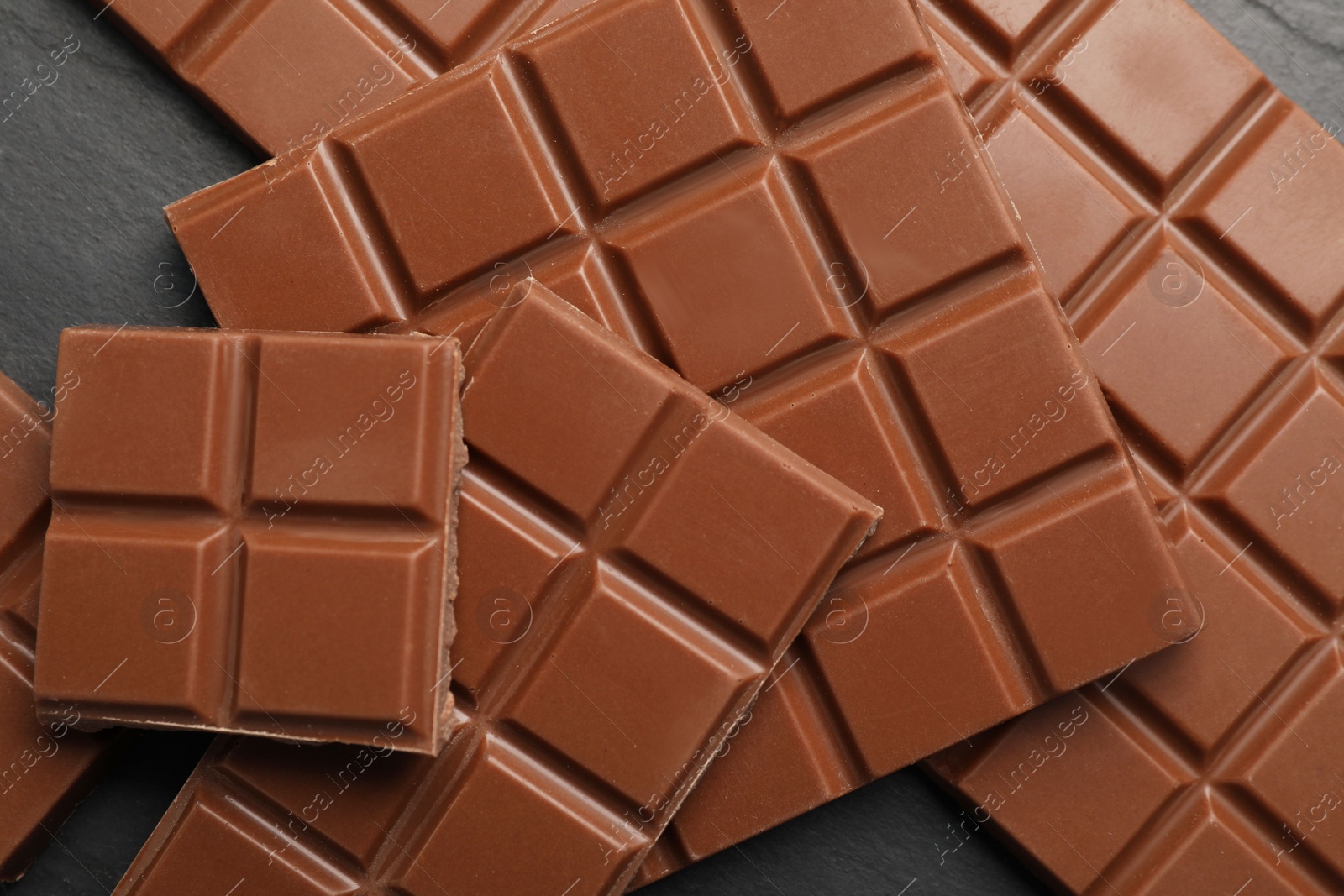 Photo of Delicious milk chocolate on black table, flat lay