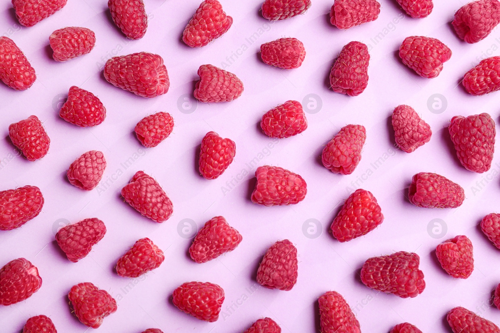 Photo of Tasty ripe juicy raspberries on pink background, top view