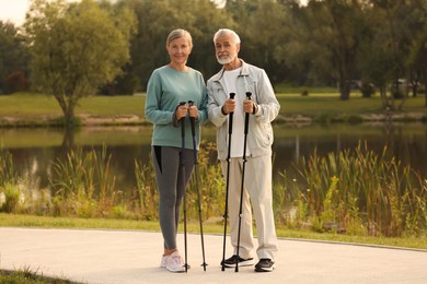 Photo of Senior man and woman with Nordic walking poles outdoors