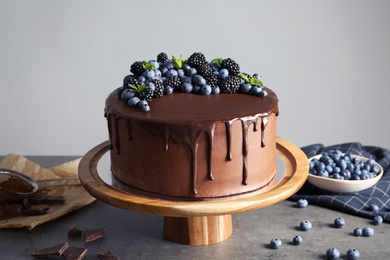 Photo of Fresh delicious homemade chocolate cake with berries on table against gray background