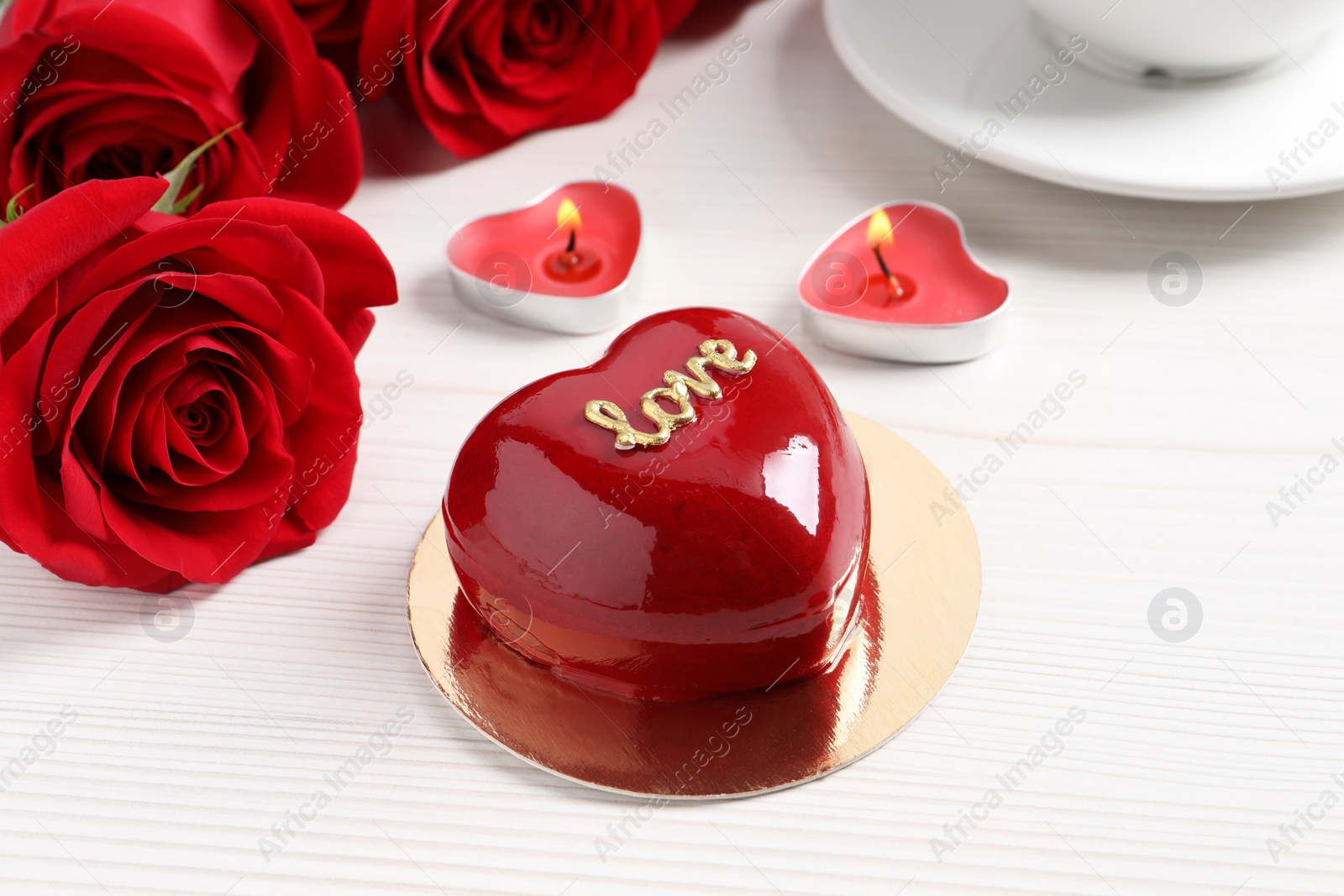 Photo of St. Valentine's Day. Delicious heart shaped cake, roses and candles on white wooden table