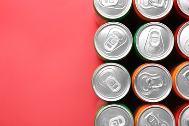 Energy drink in cans on red background, top view. Space for text