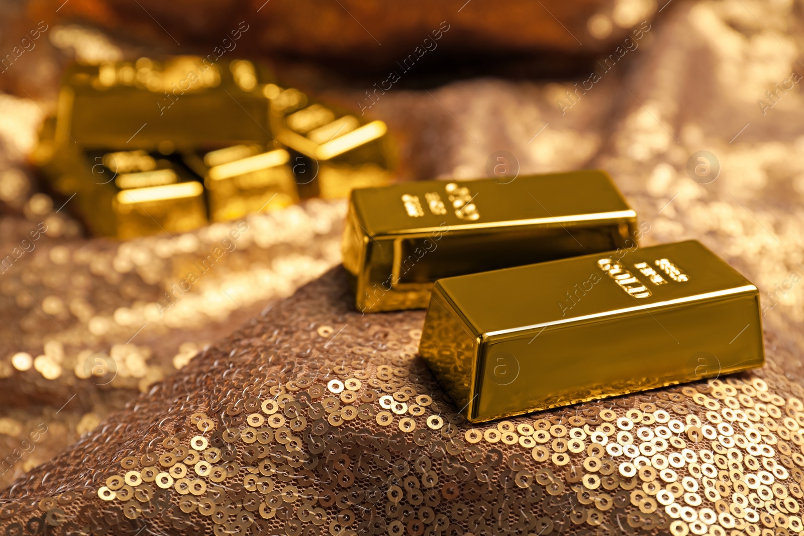 Photo of Shiny gold bars on bronze sequin fabric, closeup. Space for text