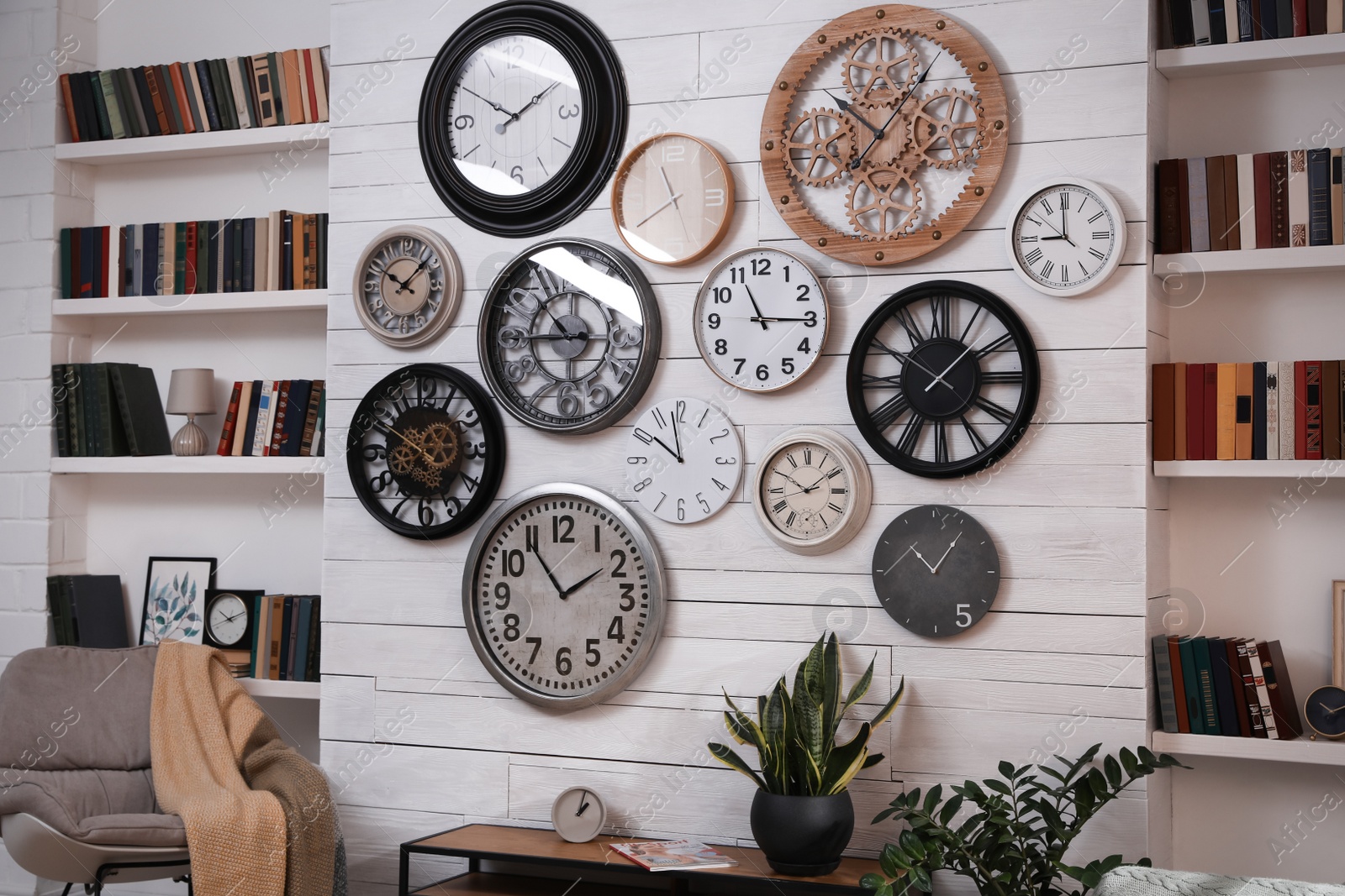 Photo of Stylish room interior with rocking chair, beautiful houseplants and collection of different clocks on white wall