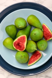 Cut and whole green figs on table, top view