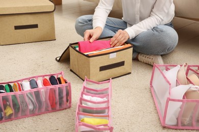 Woman folding clothes on floor at home, closeup. Japanese storage system