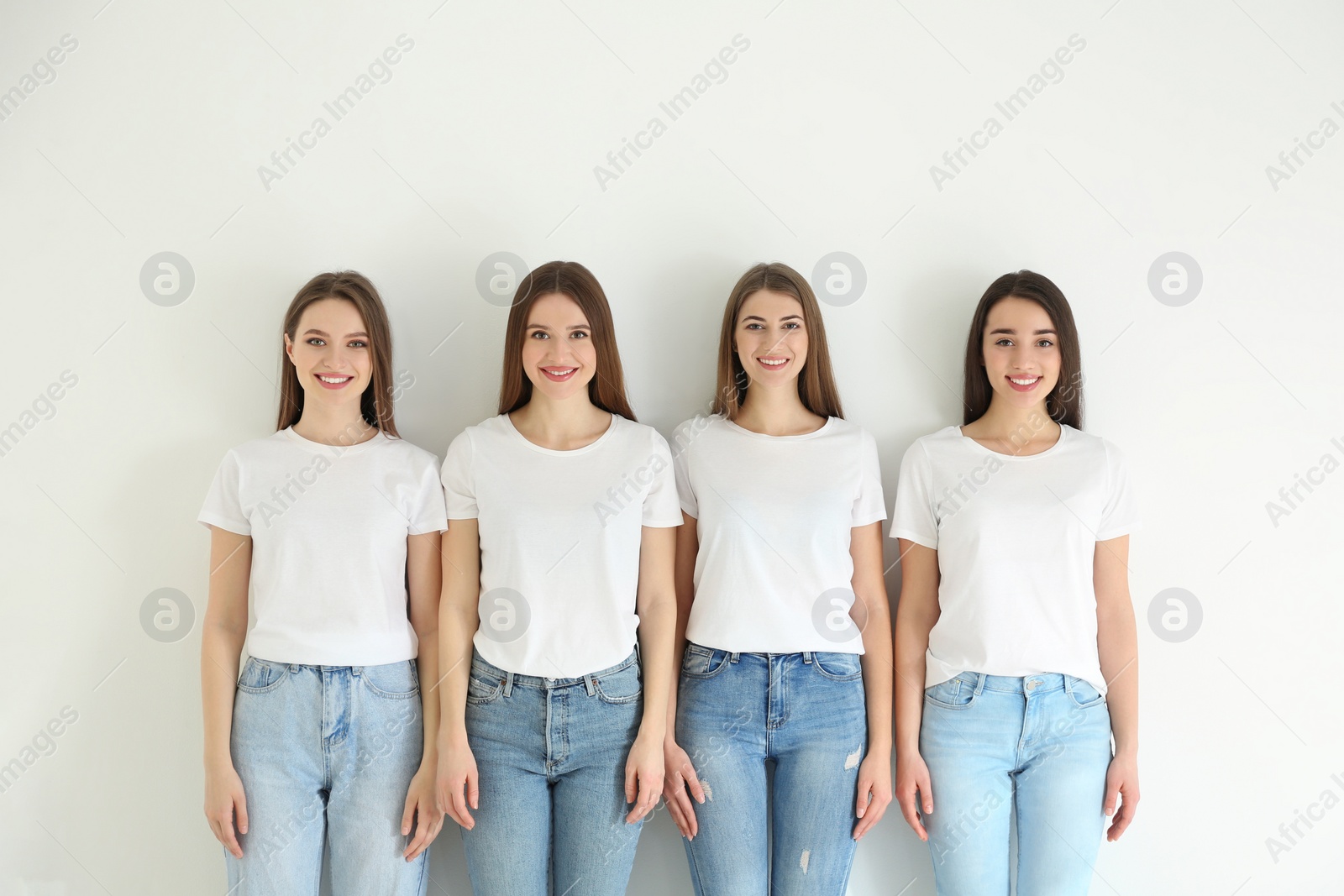 Photo of Beautiful young ladies in jeans and white t-shirts on light background. Woman's Day