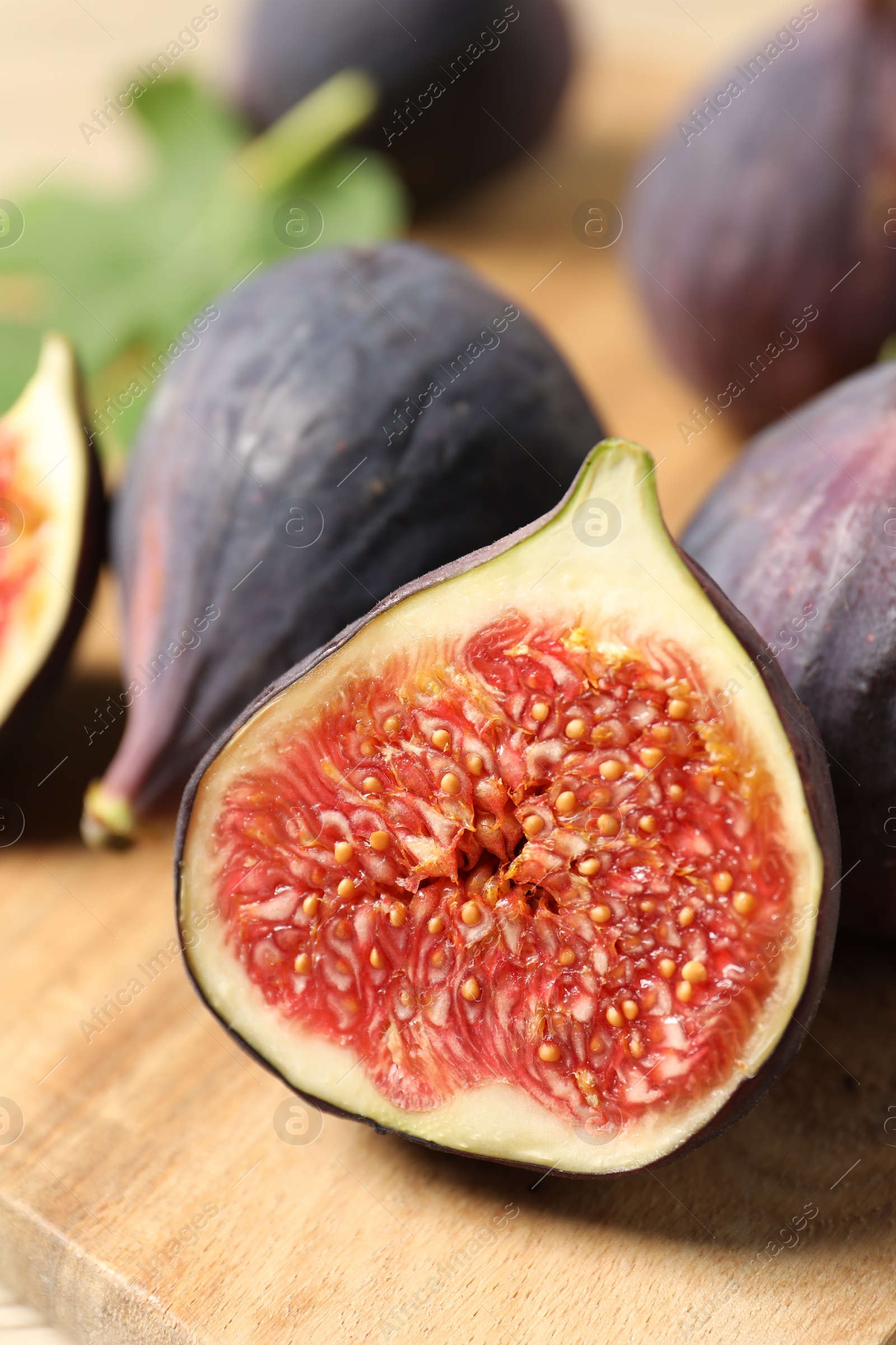 Photo of Whole and cut ripe figs on wooden table, closeup