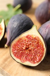 Photo of Whole and cut ripe figs on wooden table, closeup