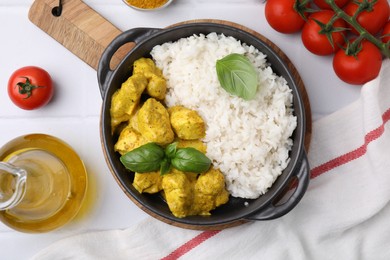 Photo of Delicious rice, chicken with curry sauce and products on white tiled table, flat lay