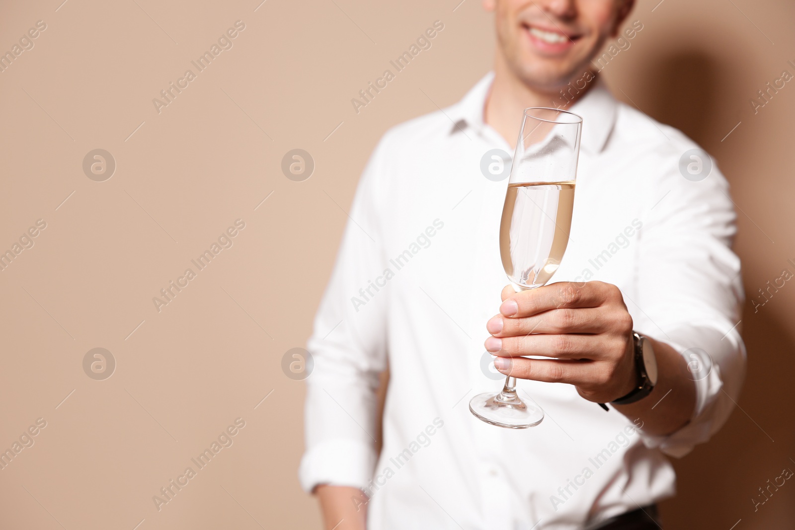 Photo of Handsome man with glass of champagne on color background, closeup. Space for text
