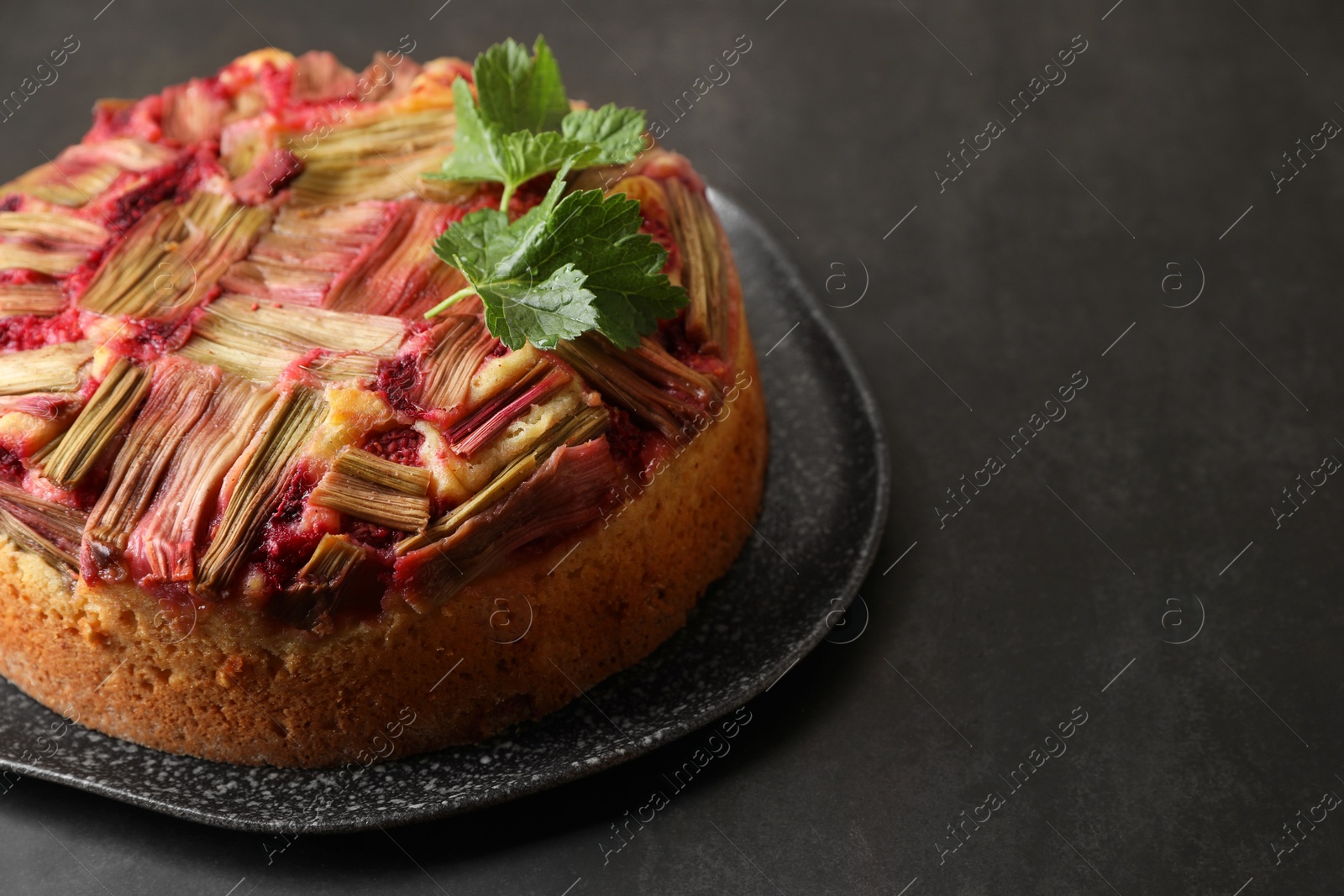 Photo of Freshly baked rhubarb pie on black table, closeup. Space for text