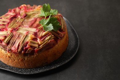 Photo of Freshly baked rhubarb pie on black table, closeup. Space for text