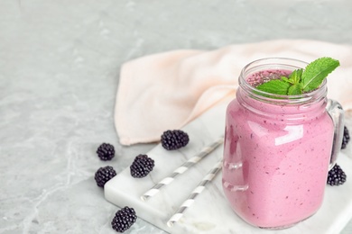 Photo of Delicious blackberry smoothie in mason jar on marble table