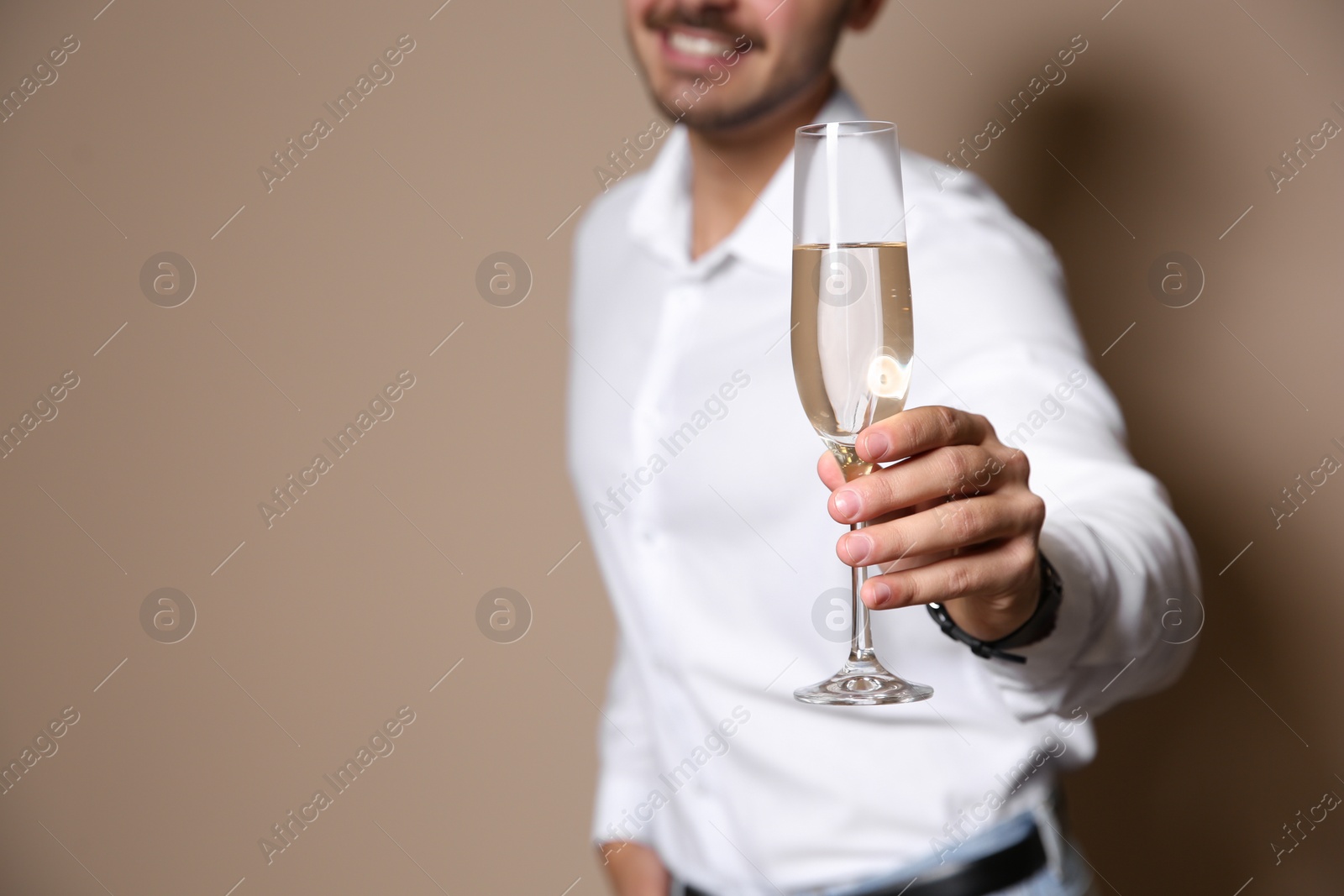 Photo of Handsome man with glass of champagne on color background, closeup. Space for text