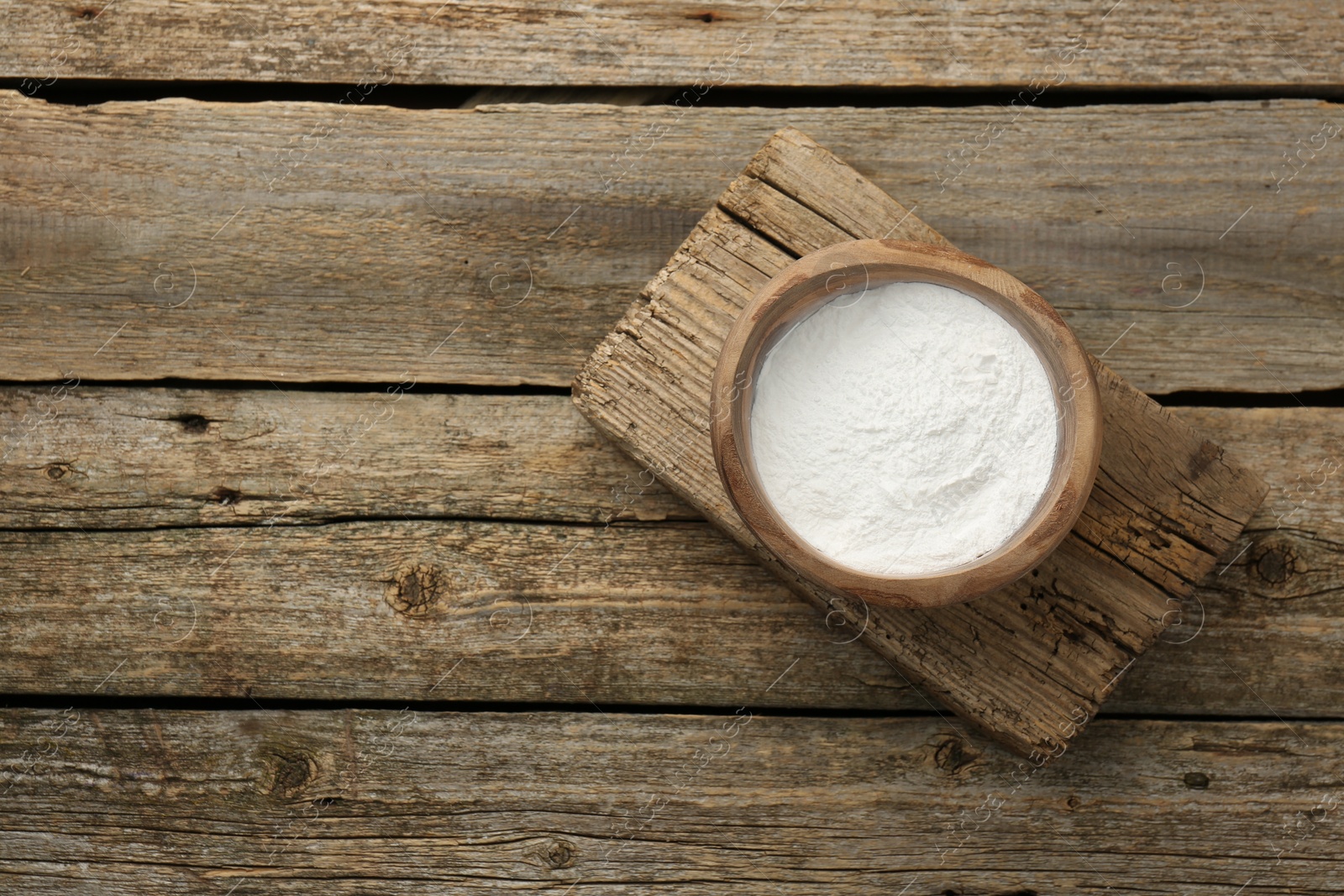 Photo of Baking powder in bowl on wooden table, top view. Space for text