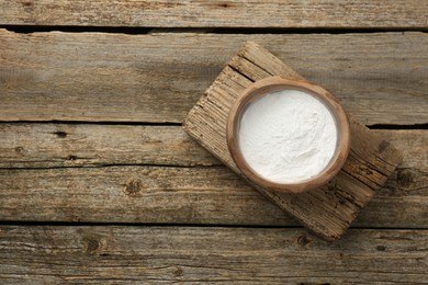 Baking powder in bowl on wooden table, top view. Space for text