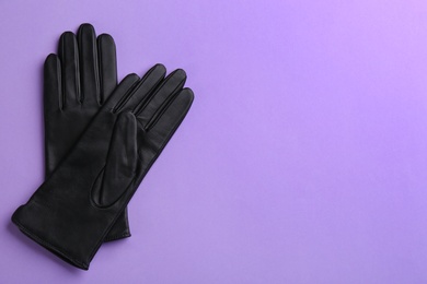 Photo of Pair of stylish leather gloves on violet background, flat lay. Space for text