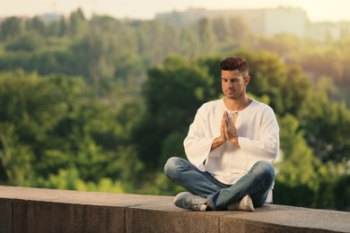 Photo of Man meditating outdoors on summer day. Space for text