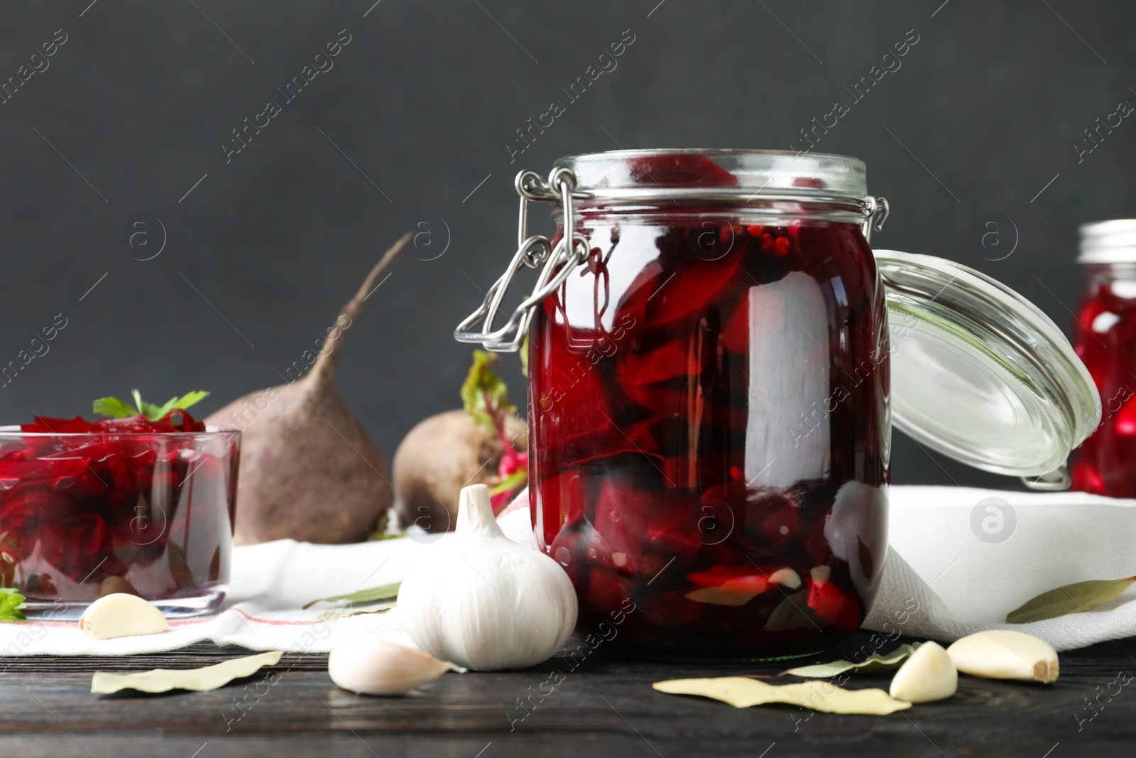 Photo of Pickled beets in glass jar on wooden table against dark background