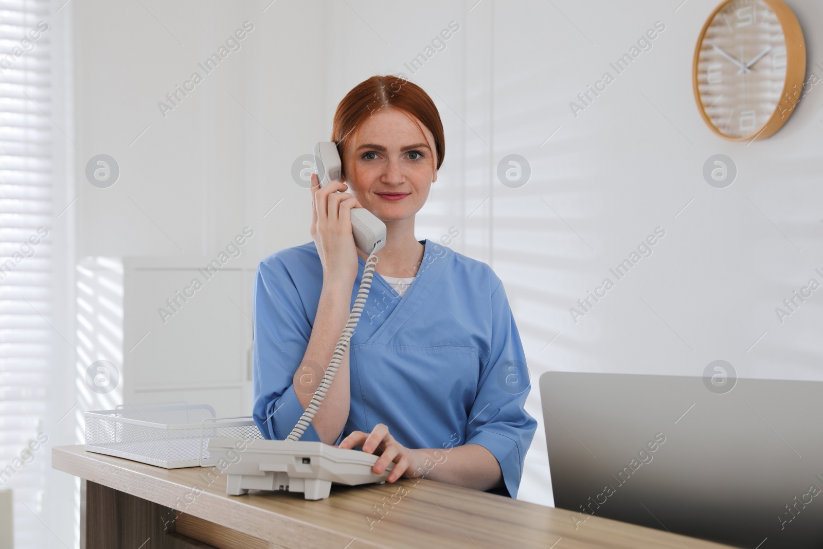Photo of Receptionist talking on phone at countertop in hospital
